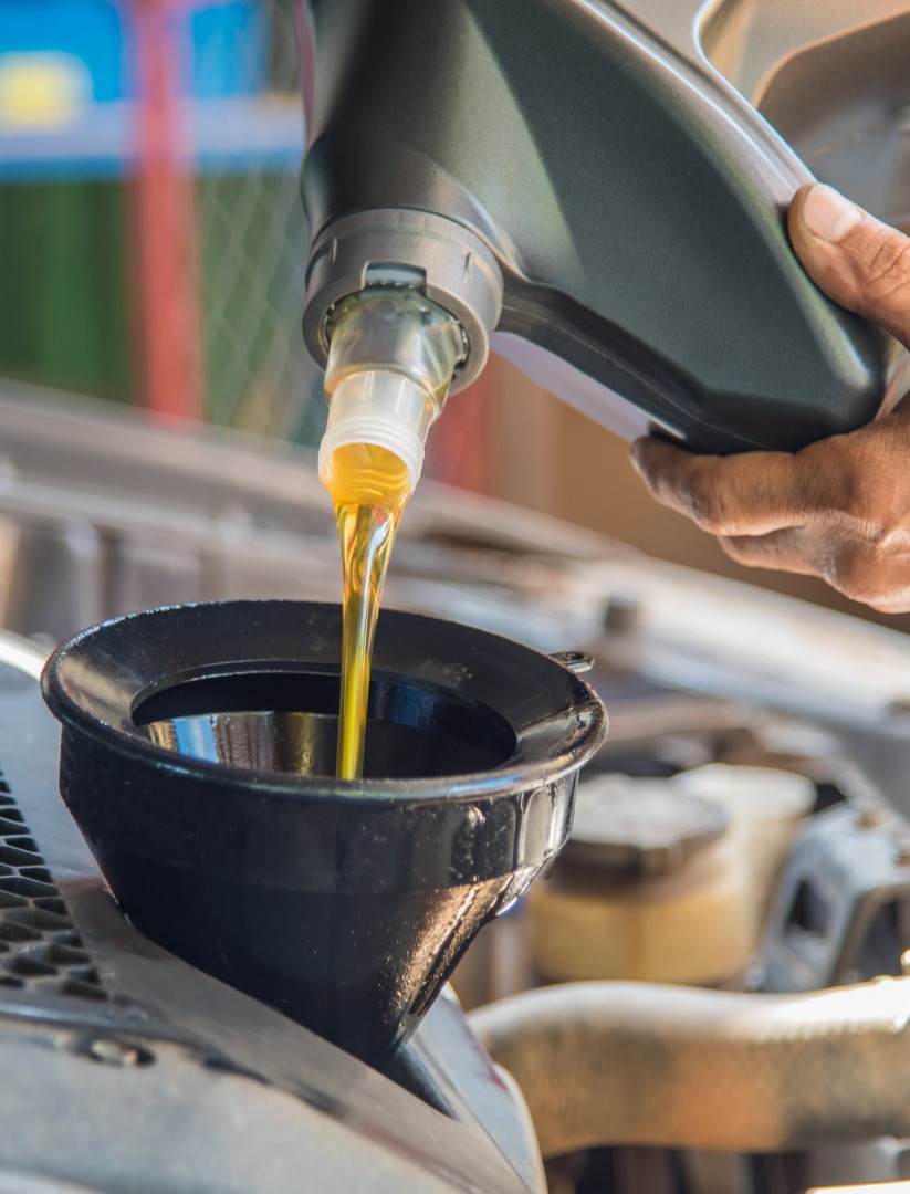 Mechanic pouring engine oil into a vehicle- MOT and Servicing Parkgate